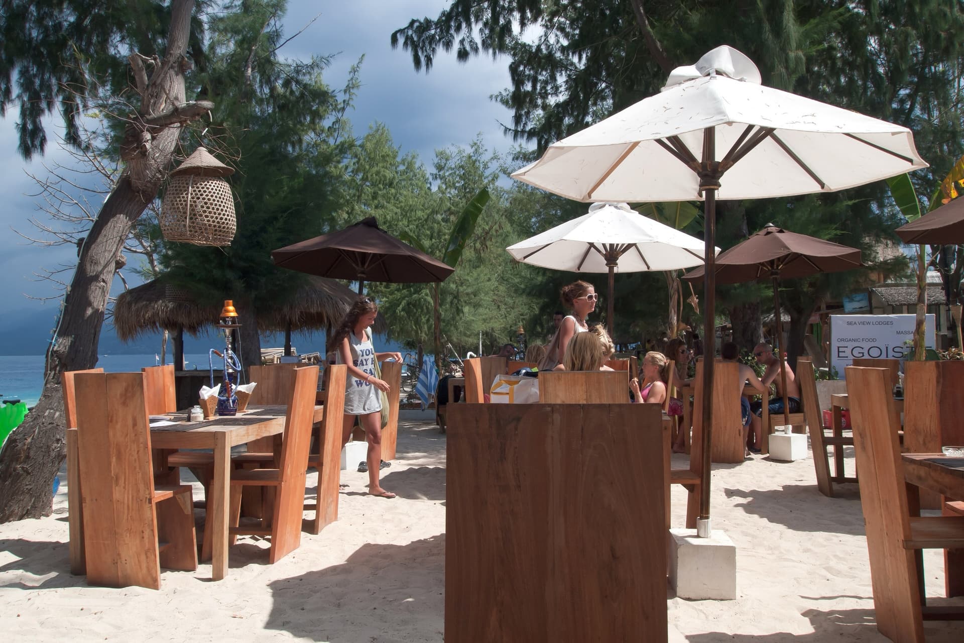 Beach bar with parasols, wooden tables and chairs on the sand
