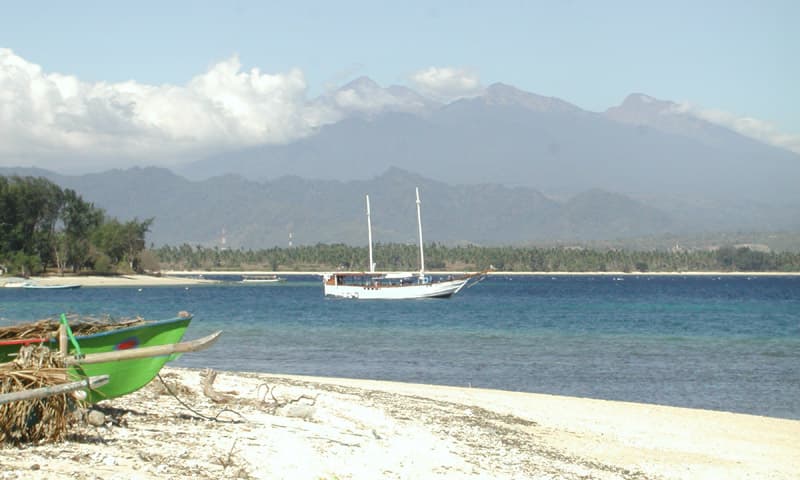 Boats moored off a Gili Air beach, with Mount Rinjani on Lombok across the strait