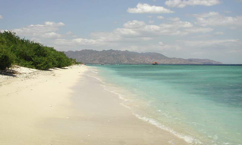 White-sand beach and turquoise shallows on Gili Meno, with the hills of Lombok behind