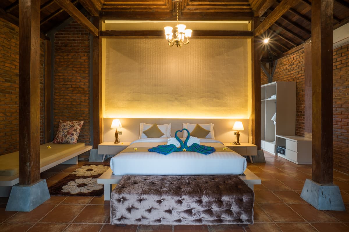 Timber joglo-style hotel room with a carved headboard wall